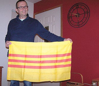 Centreville resident Bill Anders shows a South Vietnam flag, which was replaced by the Viet Kong after taking over South Vietnam. Anders spent a year in South Vietnam.