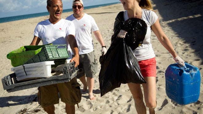 Chesterfield employees Greg Palmer, left; Zieg Oliveros, center; and Amanda Smith walk near Midtown Beach in July 2013 with some of the trash they collected during the Turtle Tuesday beach cleanup. Earlier this month, the Worth Avenue Association was honored by the Loggerhead Marinelife Center as the Go Blue Business of the Year for its Turtle Tuesday events.