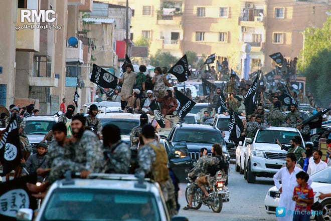 In this undated file image posted on Monday, June 30, 2014, by the Raqqa Media Center of the Islamic State group, a Syrian opposition group, which has been verified and is consistent with other AP reporting, fighters from the Islamic State group parade in Raqqa, north Syria. In the early dawn of Nov. 2, militant leaders with the Islamic State group and al-Qaida gathered at a farm house in northern Syria and sealed a deal to stop fighting each other and work together against their opponents, a prominent Syrian opposition official and a rebel commander said. Such an alliance could be a significant blow to struggling U.S-backed Syrian rebels.