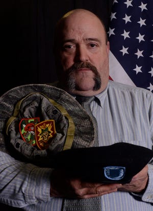 Retired Army Command Sgt. Major, Shawn Kindrew, poses for a photo with some items from his career. Photo by Laszlo Babocsi