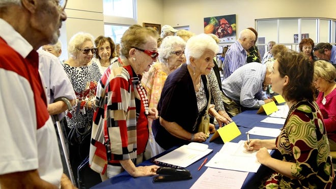 A group of seniors listens to Dana Shreve, right, with the Ruth and Norman Rales Jewish and Family Services, during the sign in for an activity at the Shirley and Barton Weisman Delray Community Center in Delray Beach.