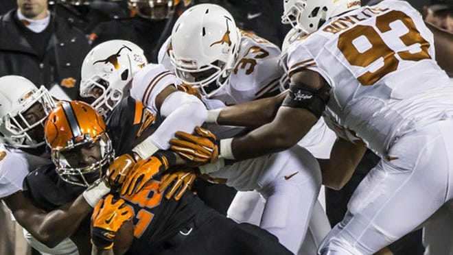 Texas Longhorns defense takes down against Oklahoma State Cowboys (28) James Washington for a loss of yardage in the NCAA college football game at Boone Pickens Stadium in Stillwater Okla. Saturday, Nov 15, 2014. (RICARDO B. BRAZZIELL / AMERICAN- STATESMAN)