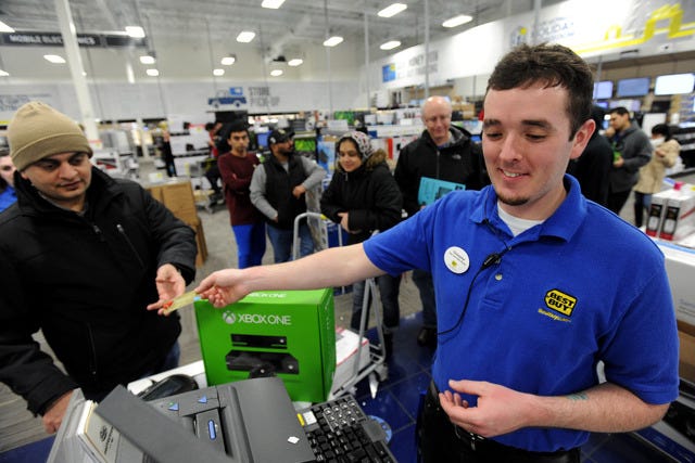 THE ASSOCIATED PRESS / Just after midnight, Best Buy employee Christopher Gervais, right, hands back a credit card after he rang up a $499.99 Xbox One game set that is a doorbuster special at the electronics retailer on Black Friday, Nov. 29, 2013, in Dunwoody, Ga. All of the store's 120 employees were on hand to ring up items when the store opened for business on Thanksgiving Day. (AP Photo/David Tulis)