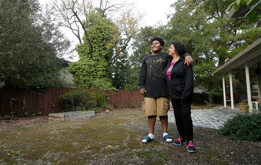 In this Nov. 13, 2014 photo, Gina Cooper, right, and her son Dante Walton, 14, pose for photos at their home in San Carlos, Calif. After a few months as nomads in 2012 when Cooper and Walton, then 12, had to vacate their home when her salary became insufficient to pay the rent, they found shelter and support with an interfaith program and stayed there five months before Cooper saved enough to be able to afford housing on her own. (AP Photo/Jeff Chiu)