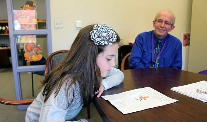 Benton Hall Academy third-grade student Olivia Brand talks about the "camonkey" creature she made as part of the Herkimer County Hunger Coalition's Half and Half Fire Safety Contest. Benton Hall Academy Principal Joe Long looks on. GATEHOUSE NEW YORK PHOTO/LINDSAY BOYLE