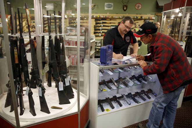 In this Saturday, Nov. 15, 2014 photo, Steven King, left, fills out paperwork before selling a handgun to first-time gun owner Dave Benne at Metro Shooting Supplies, in Bridgeton, Mo. King says heís sold two to three times more weapons in recent weeks than normal as a grand jury decides whether to indict Ferguson police Officer Darren Wilson in the shooting death of Michael Brown.