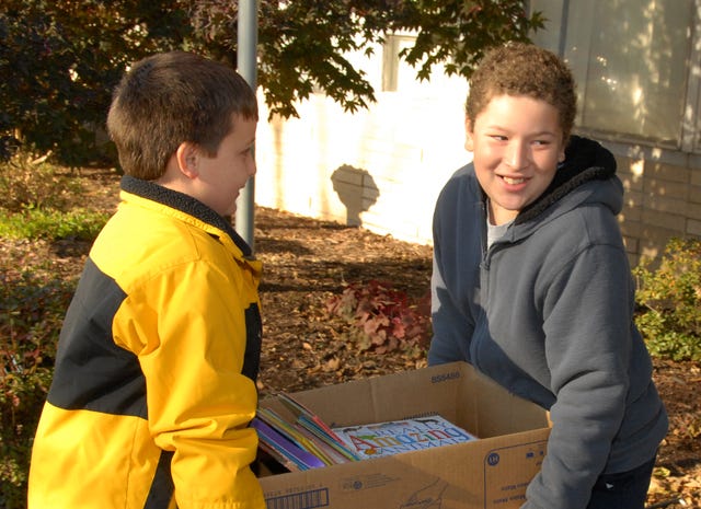 BRIAN MCMAHEN • TIMES RECORD
Jake Robbins, left, and Abraham Sharum, both fifth-graders at Christ the King Catholic School, carry one of several boxes of donated books into Lincoln Childcare Center in Fort Smith on Tuesday, Nov. 18, 2014. Christ the King students collected more than 800 books to donate to the center. Jake is the son of Erin and Rob Robbins, and Abraham is the son of Sarah Sharum. 
 BRIAN MCMAHEN • TIMES RECORD / Carrington Sosebee, a fifth-grader at Christ the King Catholic School, reads to members of Ms. Karen's 3-year-old class at Lincoln Childcare Center in Fort Smith on Tuesday, Nov. 18, 2014. Christ the King students collected more than 800 books to donate to the center. Carrington is the daughter of Kim and Roger Sosebee.