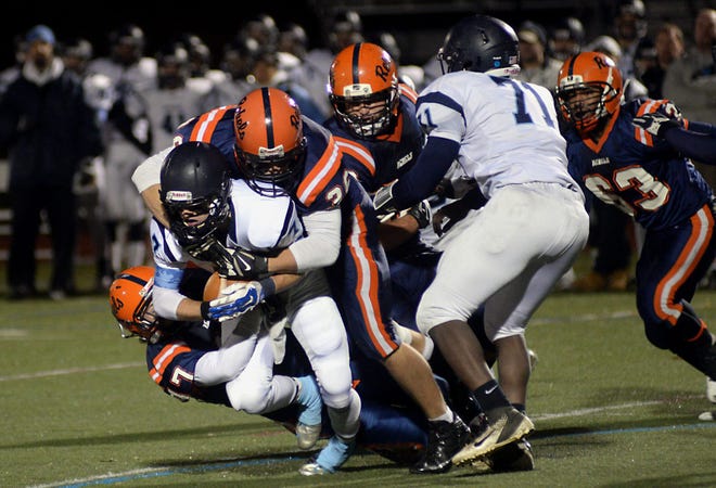 Walpole's Chris Bender (top) and James Murphy (left) bring down Medfield's Stephen Ledogar in the backfield for a sack during Friday evening's game.