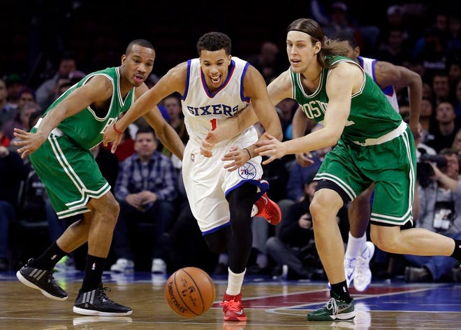 Philadelphia 76ers' Michael Carter-Williams, center, chases after a loose ball between Boston Celtics' Avery Bradley, left, and Kelly Olynyk during the first half of an NBA basketball game, Wednesday, Nov. 19, 2014, in Philadelphia.