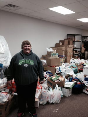 Amy Hoffmeyer is all smiles as she stands with the truck-loads of items brought in to the Hope Center's food pantry by the Stuff-A-Truck food drive.