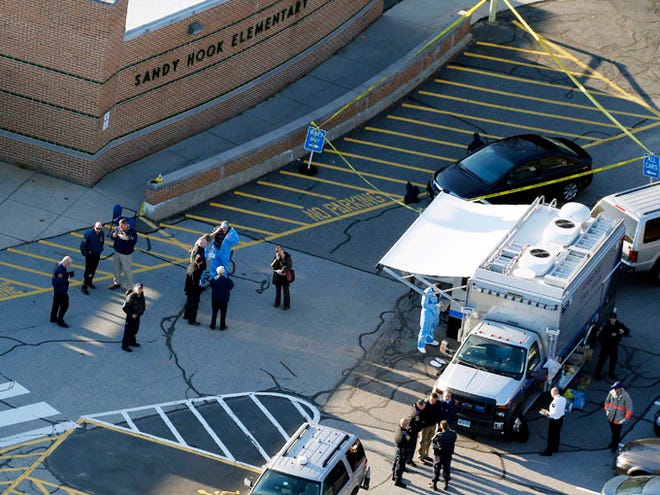 This Dec. 14, 2012, aerial file photo shows officials standing outside of Sandy Hook Elementary School in Newtown, Conn. The school system unwittingly enabled Adam Lanza's mother to "accommodate and appease" him as he became more withdrawn socially, according to a state report issued Friday on the man who carried out the 2012 massacre at Sandy Hook Elementary School.