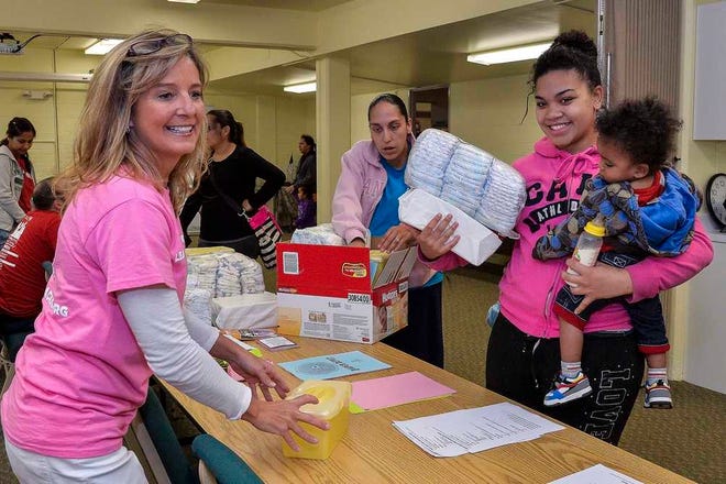Lolita Johnson with her daughter, Jai'seon Johnson, collects diapers from Junior League of Topeka volunteer Ronnie Wooten during a diaper give-away at Avondale East Education Center. The event is among the activities held at the old school, where the Community Resources Council is located.