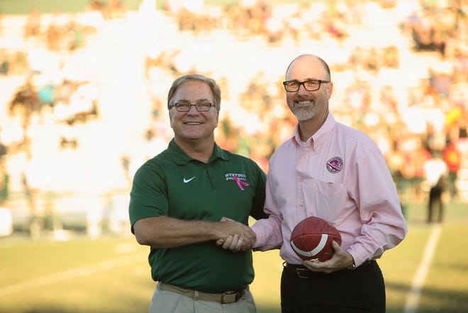 Jeff Altier, Stetson University director of athletics, shakes hands with Tim Cook, Florida Hospital DeLand CEO, as he holds the game's ball before kickoff.