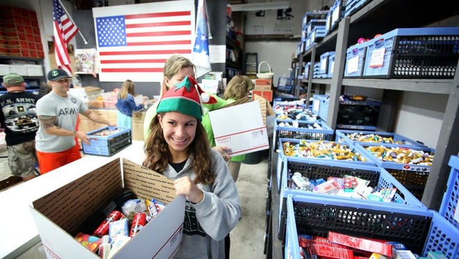 Watson B. Duncan student ambassador Ashley McKay, 12, helps Forgotten Soldiers Outreach volunteers pack special holiday “We Care” packages at their operation center in Lake Worth on Nov. 22, 2014.