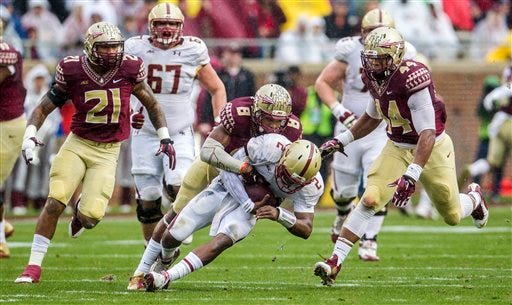 Florida State defensive back Jalen Ramsey sacks Boston College quarterback Tyler Murphy while DeMarcus Walker, right and Chris Casher, left, assist.