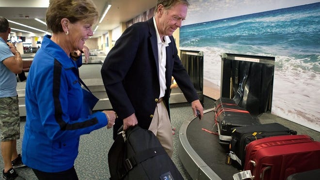 Peggy and Craig Clough of North Palm Beach take their luggage off of the baggage carousel at Palm Beach International Airport.