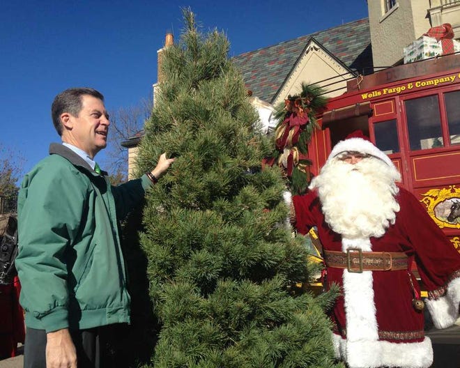 Gov. Sam Brownback and Santa Claus stand next to the 2014 Kansas Christmas Tree which was delivered Tuesday morning to Cedar Crest, the governor's mansion in west Topeka.