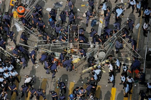 Police officers clear a metal barricades while others tear down tents and canopies and carry away other obstructions after bailiffs issued a warning to the crowd that they would start enforcing the court-ordered clearance at an occupied area in Mong Kok district of Hong Kong Wednesday, Nov. 26, 2014. Hong Kong authorities cleared street barricades from the pro-democracy protest camp in the volatile Mong Kok district for a second day Wednesday after a night of clashes in which police arrested 116 people. (AP Photo/Vincent Yu)