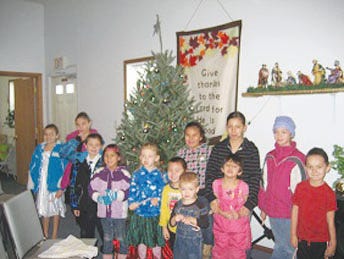 Children at Dakota Baptist in Ft. Totten gather around the real Christmas tree given by a generous donor.