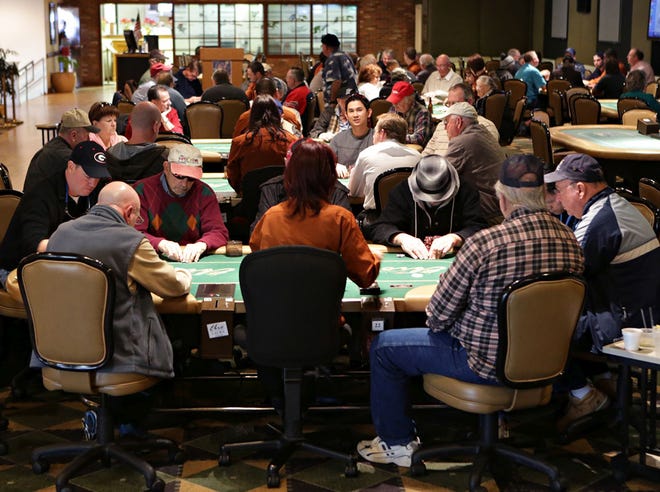 Patrons gather around multiple tables in the poker room at Ebro Greyhound Park. The park is looking to add slot machines, but legislative action would be required.