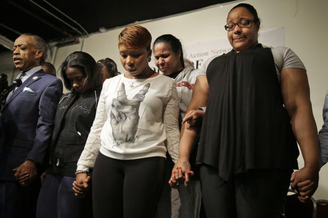 Emerald Garner, daughter of Eric Garner, right, Esaw Garner, Eric Garner's wife, second from right, Lesley McSpadden, mother of Michael Brown, center, and Kimberly Michelle Ballinger, the domestic partner of Akai Gurley, second from left, join Al Sharpton in a prayer during a news conference at the National Action Network headquarters in New York, Wednesday. On the day before Thanksgiving, Sharpton brought together the families of Michael Brown, Eric Garner and Akai Gurley, all black men recently killed by police officers. (AP Photo/Seth Wenig)