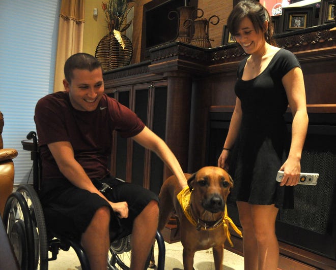 Kirk Crandall, who was paralyzed in a car crash two years ago, pets Zayla with his left arm as his sister Gabrielle Myrick watches in New Smyrna Beach. The Spruce Creek High School graduate’s friends and family are holding a fundraiser for him tonight at World of Beer in Port Orange.