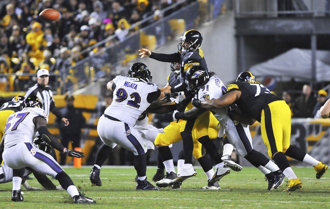 Steelers QB Ben Roethlisberger gets the pass off as he is hit by a pile of Ravens.