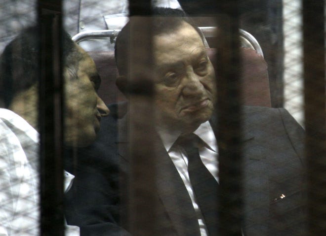 Ousted Egyptian President Hosni Mubarak sits in the defendants cage behind protective glass during a court hearing May 21, 2014, as he listens to his son Gamal, left, in Cairo, Egypt. On Saturday, Nov. 29, a court dismissed criminal charges against Mubarak in the killing of more than 900 protesters during the 2011 uprising against his rule.