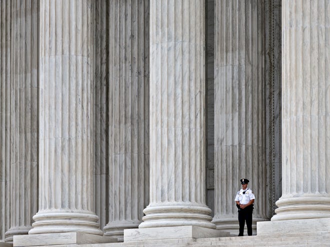 FILE - This Oct. 7, 2014, file photo shows a police officer dwarfed amid the marble columns of the U.S. Supreme Court in Washington. Anthony Elonis claimed he was just kidding when he posted a series of graphically violent rap lyrics on Facebook about killing his estranged wife, shooting up a kindergarten class and attacking an FBI agent. But his wife didn't see it that way. Neither did a federal jury. In a far-reaching case that probes the limits of free speech over the Internet, the Supreme Court on Monday is considering whether Elonis' Facebook posts, and others like it, deserve protection under the First Amendment. (AP Photo/J. Scott Applewhite, File)