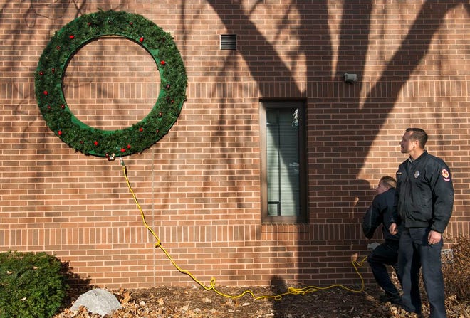 Peoria firefighters Rick Waldron, right, and Eric Crowhurst power up the wreath on the outside of the department's central fire station on Monroe Street Monday. The wreath is hung annually for the holiday season to draw public awareness to the greater risk of fire in the season.