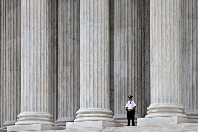 This Oct. 7, 2014, file photo shows a police officer dwarfed amid the marble columns of the U.S. Supreme Court in Washington. Anthony Elonis claimed he was just kidding when he posted a series of graphically violent rap lyrics on Facebook about killing his estranged wife, shooting up a kindergarten class and attacking an FBI agent. But his wife didn't see it that way. Neither did a federal jury. In a far-reaching case that probes the limits of free speech over the Internet, the Supreme Court on Monday is considering whether Elonis' Facebook posts, and others like it, deserve protection under the First Amendment. (AP Photo/J. Scott Applewhite, File)