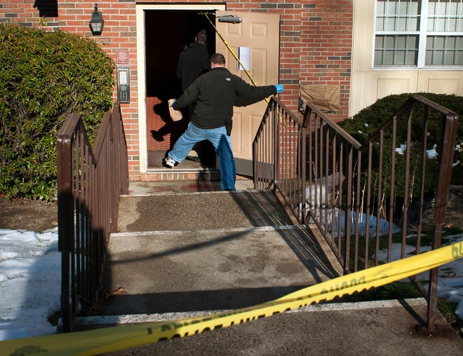 An investigator enters the apartment building Monday on Duncannon Avenue in Worcester, stepping over what appears to be blood.
