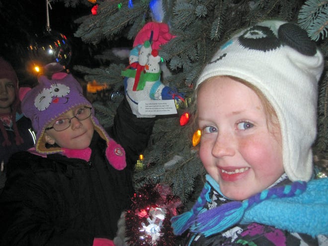 Arian Dangelo, left, Natalee Perkins, middle, and Laycee LaBarge, right, hang homemade ornaments on the town Christmas tree at Saturday night's Lions Club Christmas Tree Lighting. Photo by Kiki Evans