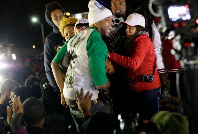 In this Nov. 24, 2014 file photo Louis Head, center front, Michael Brown's stepfather, and Brown's mother Lesley McSpadden, wearing sunglasses, react as they listen to the announcement that a grand jury decided not to indict Ferguson police officer Darren Wilson who fatally shot Brown. St. Louis County Police said Tuesday, Dec. 2, 2014 that authorities want to talk to Head about his angry comments as part of a broader investigation into arson, vandalism and looting that followed the Nov. 24 grand jury announcement. (AP Photo/Charlie Riedel, File)