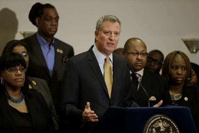 New York City Mayor Bill de Blasio, surrounded by community leaders, speaks to reporters about the grand jury's decision in the Eric Garner case in the borough of Staten Island in New York, Wednesday, Dec. 3, 2014. A grand jury cleared the white New York City police officer Wednesday in the videotaped chokehold death of Garner, an unarmed black man, who had been stopped on suspicion of selling loose, untaxed cigarettes, a lawyer for the victim's family said. A video shot by an onlooker and widely viewed on the Internet showed the 43-year-old Garner telling a group of police officers to leave him alone as they tried to arrest him. The city medical examiner ruled Garner's death a homicide and found that a chokehold contributed to it. (AP Photo/Seth Wenig)