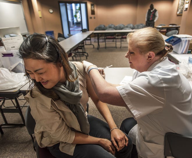 Cumberland HealthNET and Walgreens hosted another flu clinic at City Hall. Walgreens Pharmacy manager Brandy Stroud gives a free flu shot to Minjoo Ko , Friday Nov. 21, 2014 .