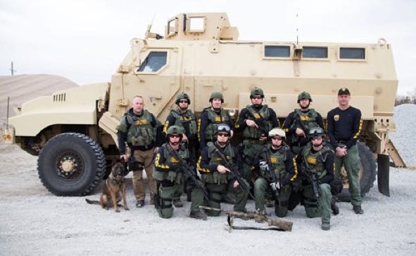 In this undated handout photo provided by the Lancaster County Sheriff's Office, the Lancaster County Sheriff's Office Tactical Response Unit poses in front of a MRAP (Mine-Resistant Ambush Protected) Armored Vehicle, a surplus military vehicle that came through a federal program, in Lincoln, Neb.