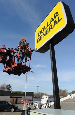 National Sign Corp. workers both named Mike Furtado, of no relation, apply frame pieces to the sign being installed in front of Dollar General in Tiverton on Thursday.