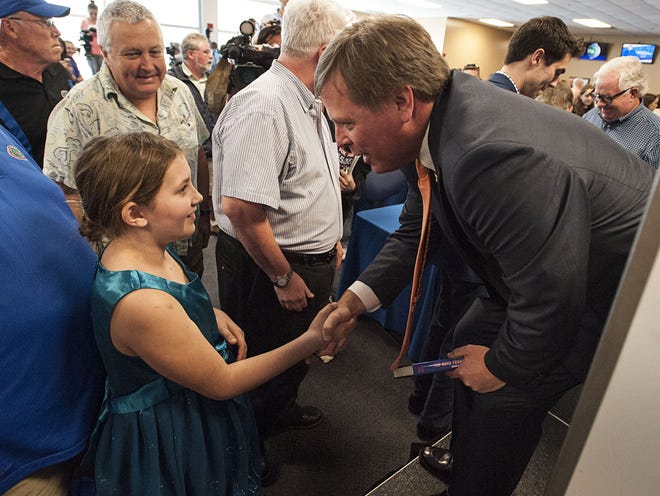 Jim McElwain, Florida's new head football coach, speaks to a young Gators fan at an NCAA college football news conference Saturday in Gainesville.