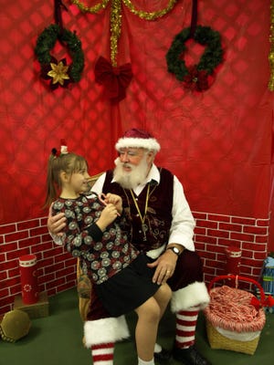 Palm Coast resident Bill Kampf, as Santa Claus, listens to the holiday wishes of a young girl in this photo from 2011.