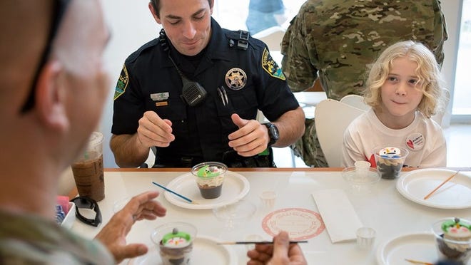 Jake Lemon (right), 9, of Boynton Beach, decorates cupcakes with Boynton Beach Police Officers Justin Spence (center) and Brian Goldfuss at Sweet Surrender bakery on Dec. 6, 2014 in Boynton Beach. The event was Lemon’s idea to raise money for the Community Caring Center of Greater Boynton Beach and to allow children the opportunity to interact with local law enforcement.