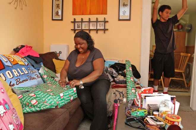 Stacy Smith, of East Providence, has spent $80 on Christmas toys and clothes for an 8-year-old girl in an East Greenwich group home for foster children. In the background is her son Jordan.
