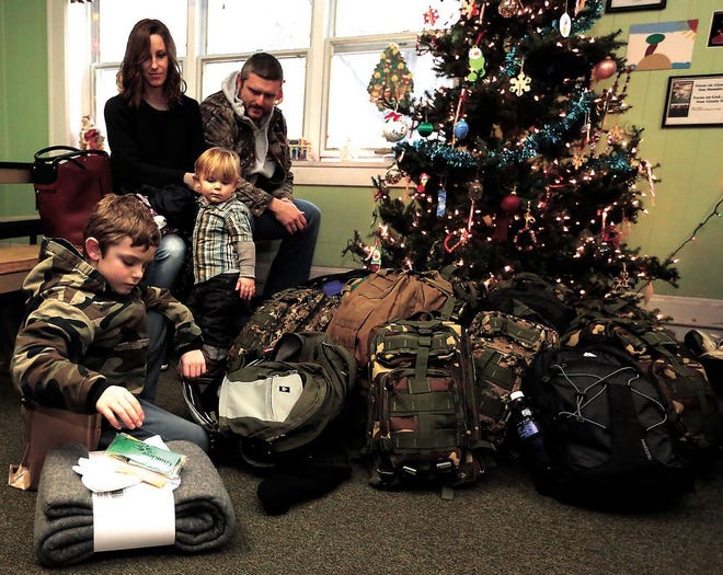 Kim and Kyle Chenault sit with son Krew as their 7-year-old son, Porter, shows what is in the backpacks that he raised money to buy and donate to the Tuscarawas County Friends of the Homeless shelter.