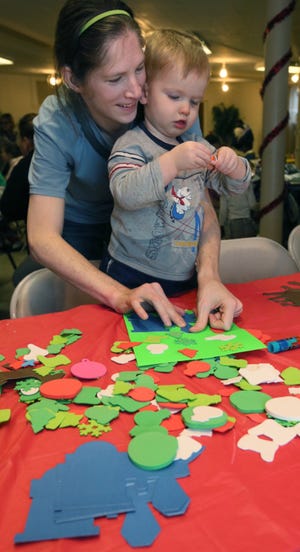Kristen Wenner and her 22-month old son, Jacob, work at the craft table during the Kenmore Holiday Celebration at The Church on the Boulevard on Saturday in Akron. (Phil Masturzo/Akron Beacon Journal)