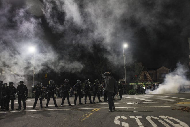 Demonstrators toss out smoke bombs during a march in Berkeley, California. Two officers were injured Saturday night as the protest over police killings turned violent with protesters smashing windows and throwing rocks at police.