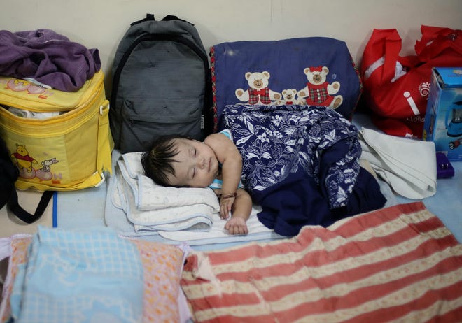 Filipino Jonrey Pawang sleeps beside his family's belongings as they take refuge at a school used as an evacuation center, in Legazpi, Albay province, eastern Philippines Saturday, Dec. 6, 2014. Typhoon Hagupit slammed into the central Philippines' east coast late Saturday, knocking out power and toppling trees in a region where 650,000 people have fled to safety, still haunted by the massive death and destruction wrought by a monster storm last year. (AP Photo/Aaron Favila)