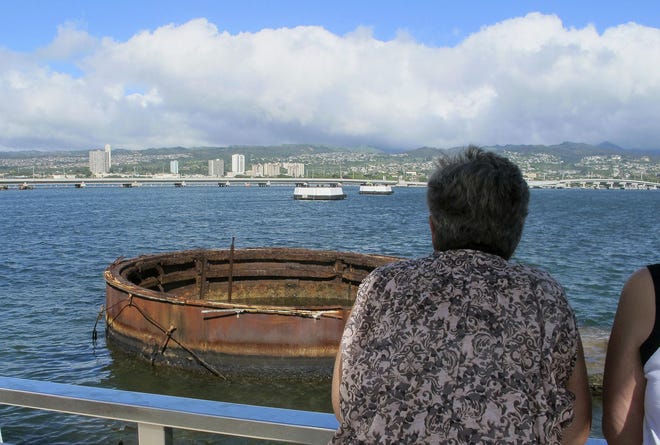 This Nov. 21, 2014 photo shows visitors looking out at the sunken USS Arizona from a memorial atop the rusting battleship in Pearl Harbor, Hawaii. The USS Arizona is one of the nation's most hallowed sites, an underwater grave for more than 900 sailors and Marines killed when Japan bombed Pearl Harbor and sank their ship in 1941, but it's now the scene of alleged rampant mismanagement. (AP Photo/Audrey McAvoy)