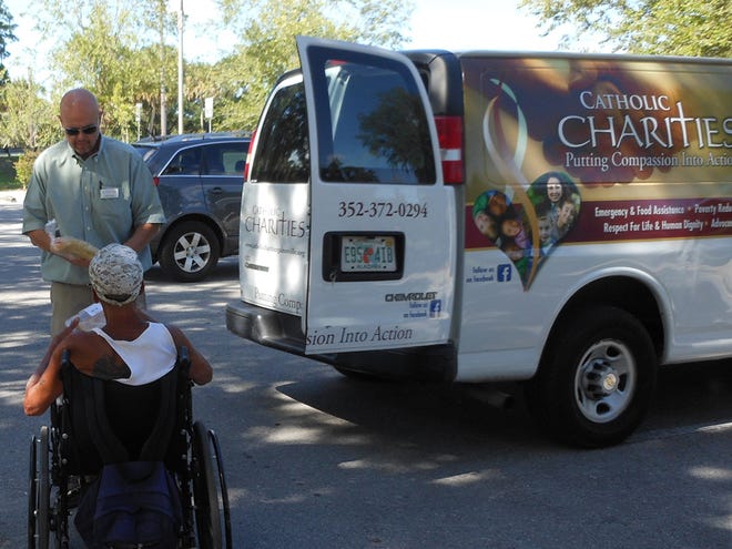 A volunteer at Catholic Charities of Gainesville distributes food. In addition to feeding the hungry, the nonprofit also provides limited financial assistance.