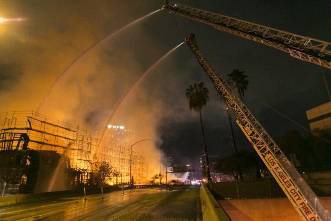 Los Angeles County firefighters battle a fire at an apartment building under construction next to the Harbor CA-110 Freeway. The building was not occupied.