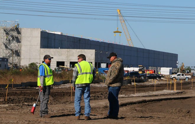 Construction workers at the Trader Joe’s regional distribution center site in Daytona Beach on Tuesday. The center, which is being built just north of Dunn Avenue, east of Interstate 95, is expected to create at least 450 jobs.